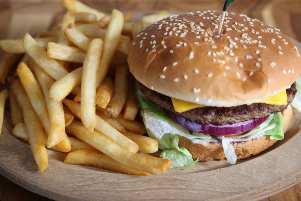 Cheeseburger with lettuce, tomato and red onion, with a side of fries