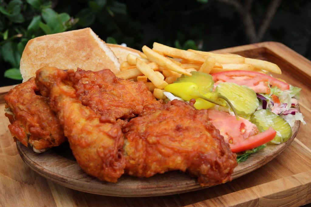 Fried chicken with fries, a roll, salad and pickled peppers