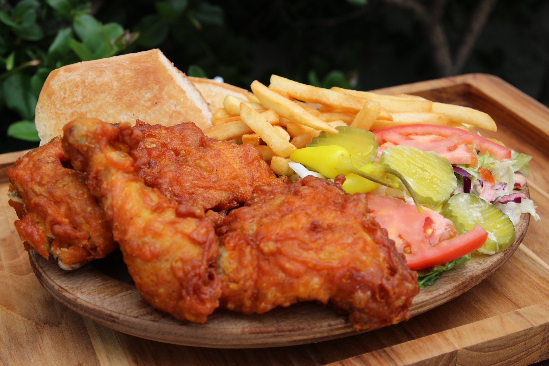 Fried chicken with fries, a roll, salad and pickled peppers